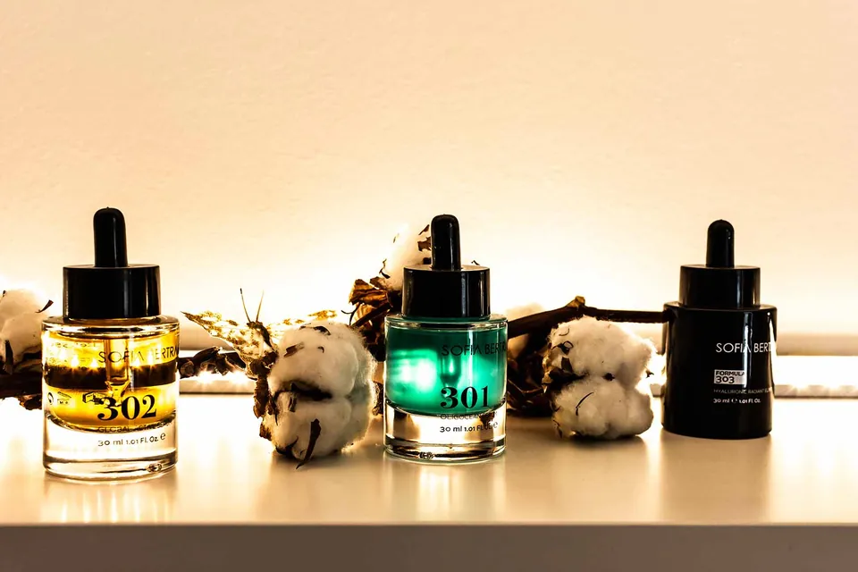 Frascos de cosmética sobre una repisa, con flores de algodón